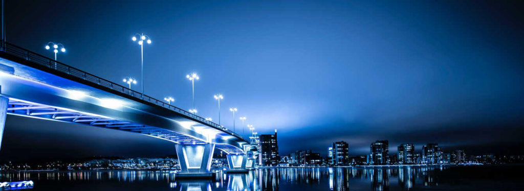 bridge-at-night-with-the-lights-on-across-river-1024x374